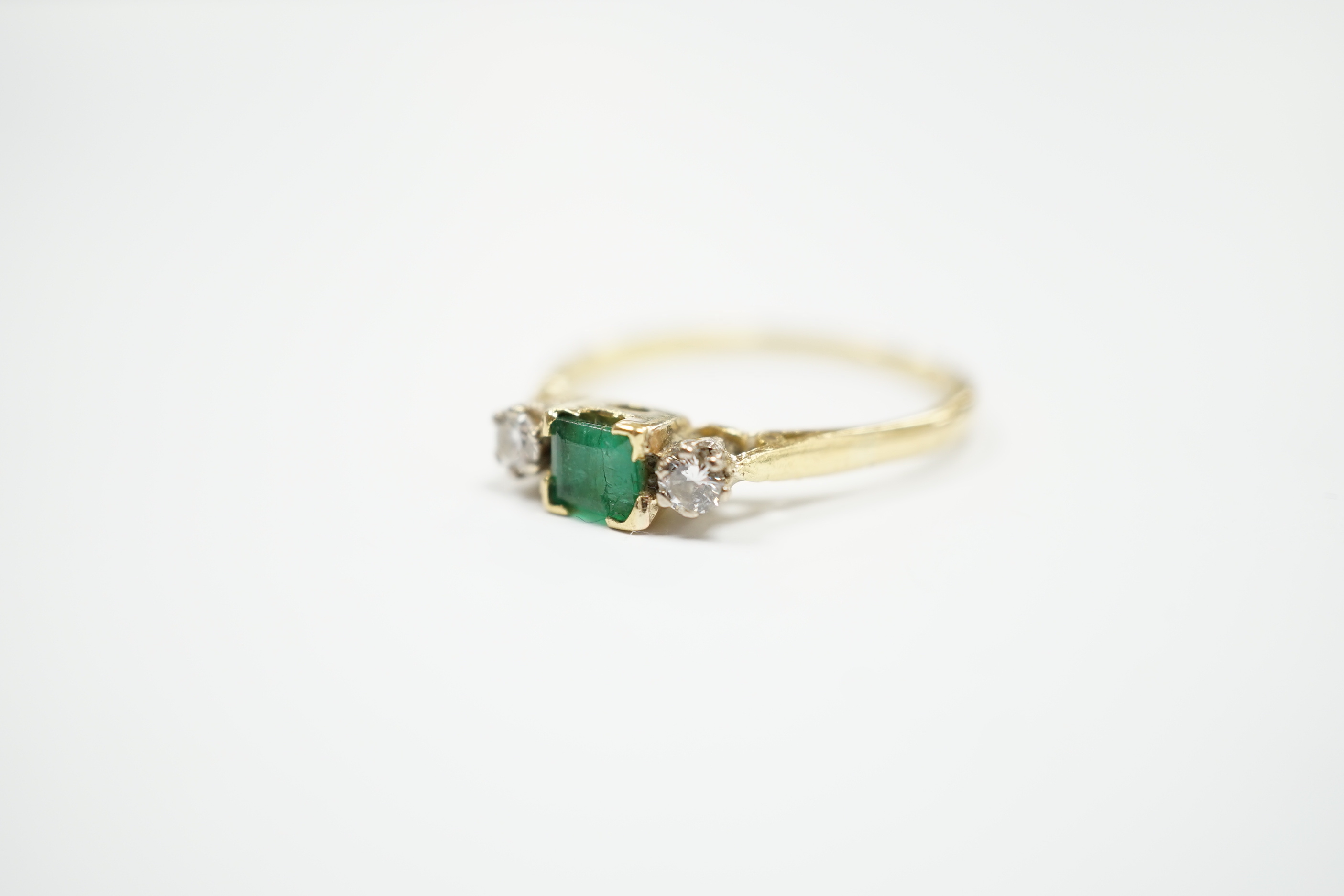 An 18ct and plat, single stone emerald and two stone diamond set ring, size Q/R, gross weight 2.6 grams.